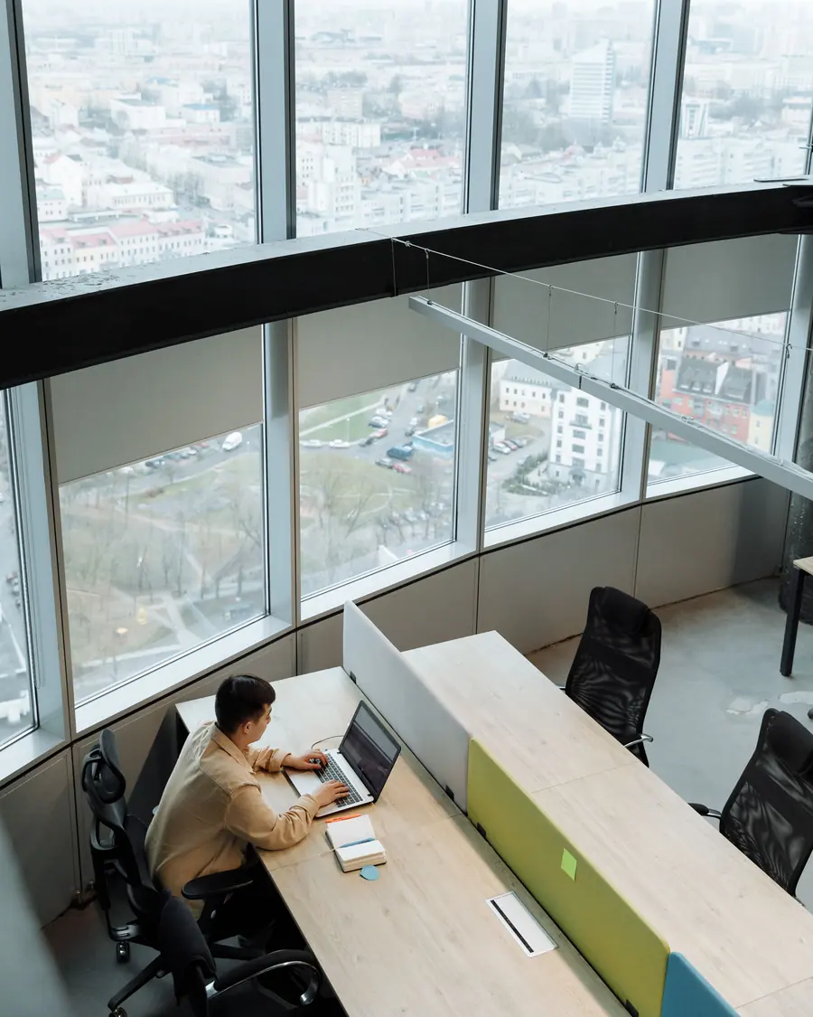 Developer working at a desk beside floor-to-ceiling city-view windows