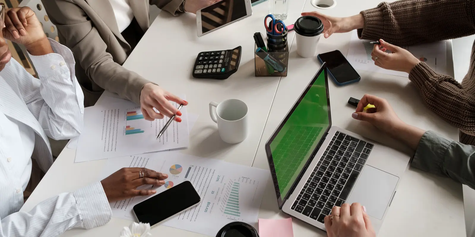 Team reviewing business charts and reports around a meeting table