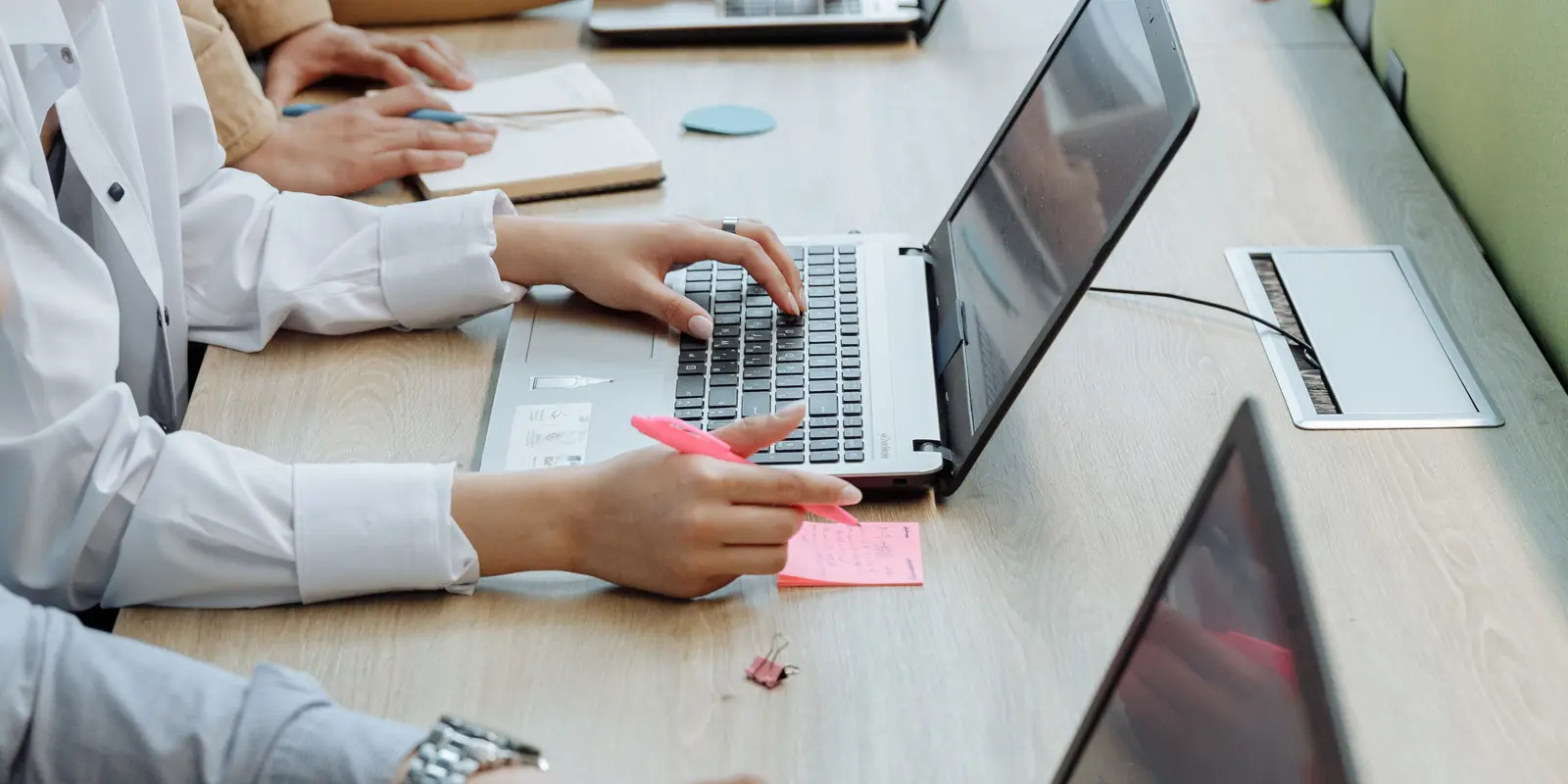 Sales team members typing on laptops at a shared desk